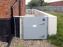 Swing-hinged flood gate at utility site